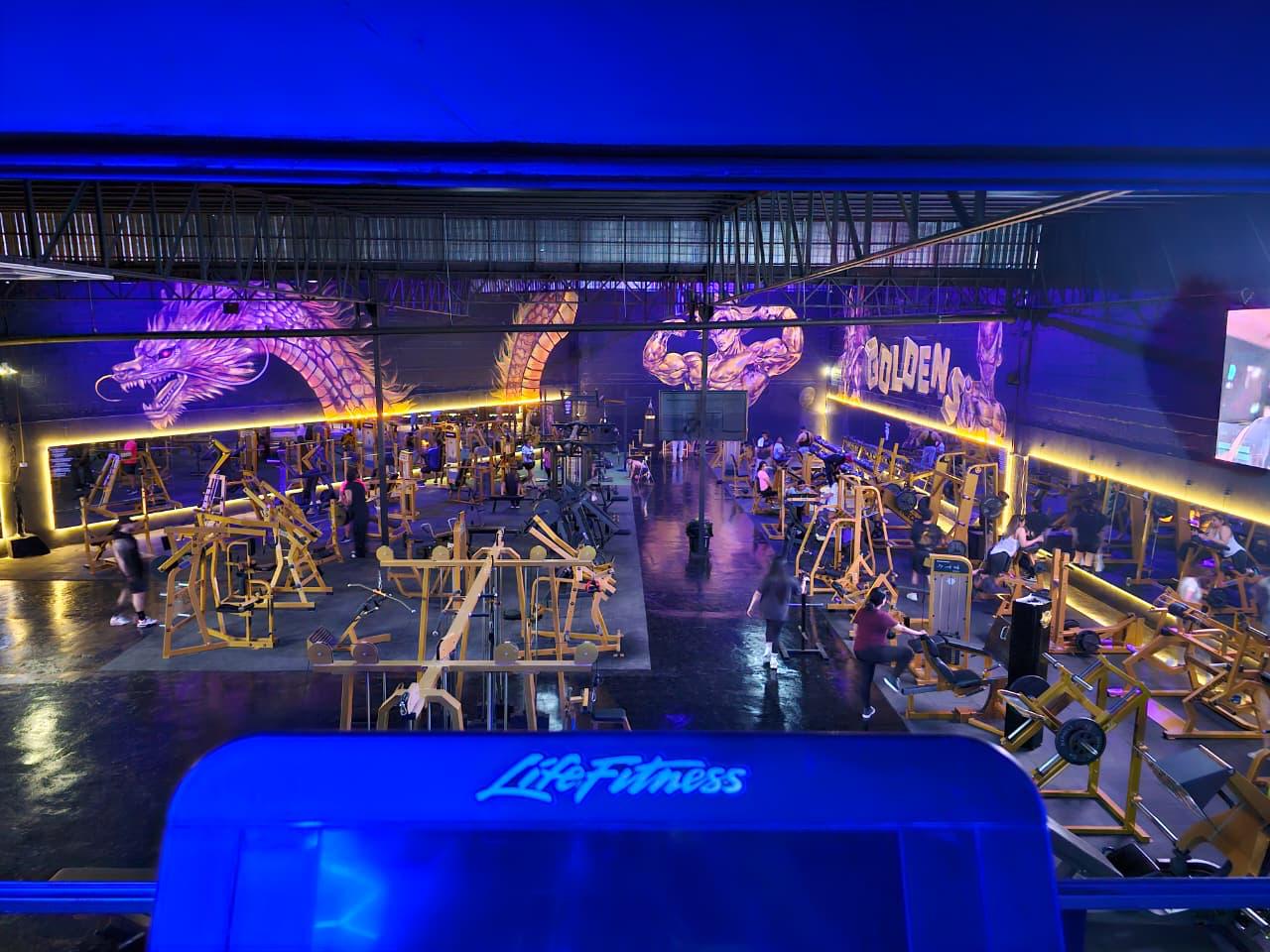 Interior de Golden's Gym: nave de doble altura con máquinas doradas